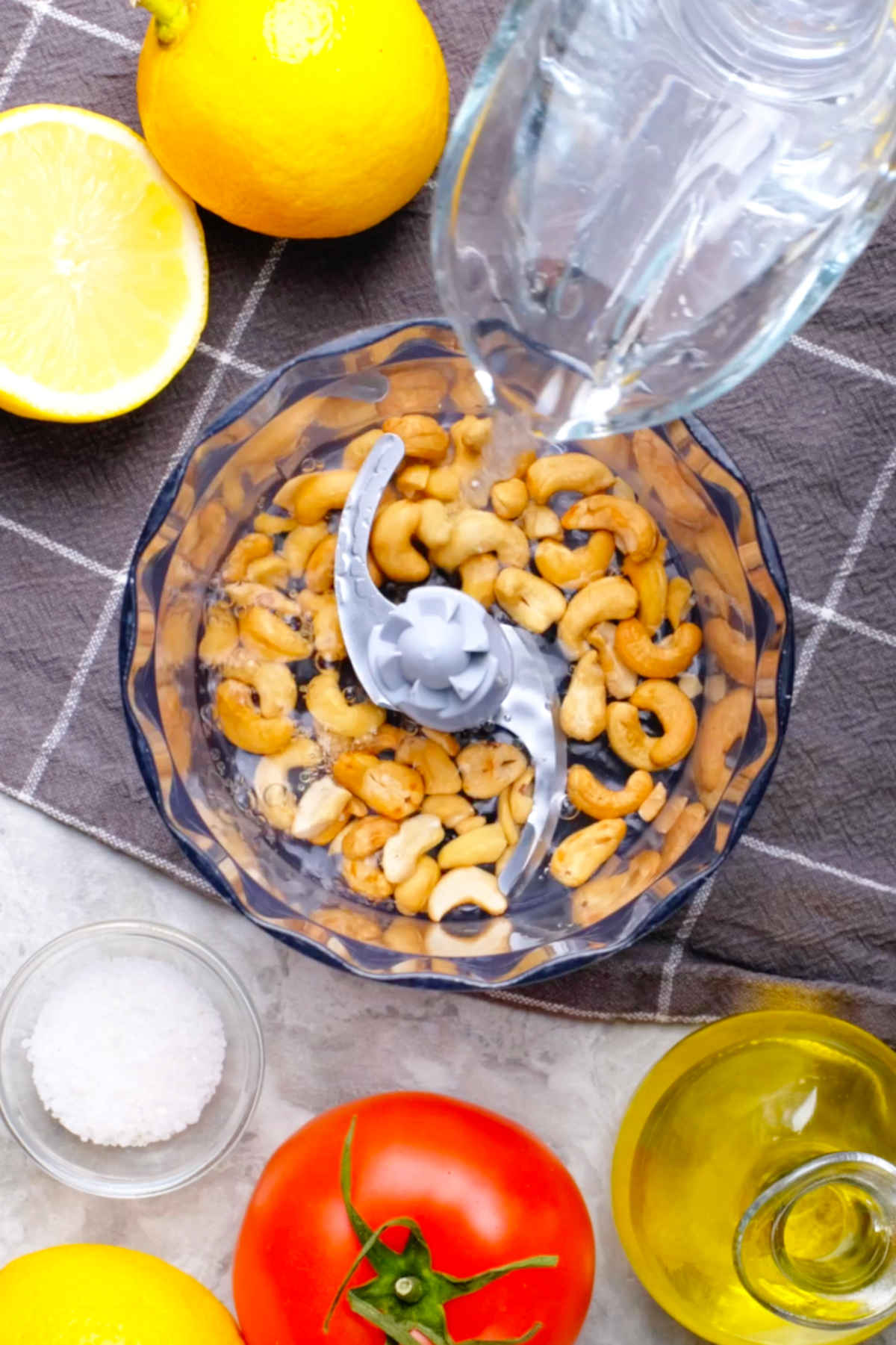 Cashews in a food processor with water being added.