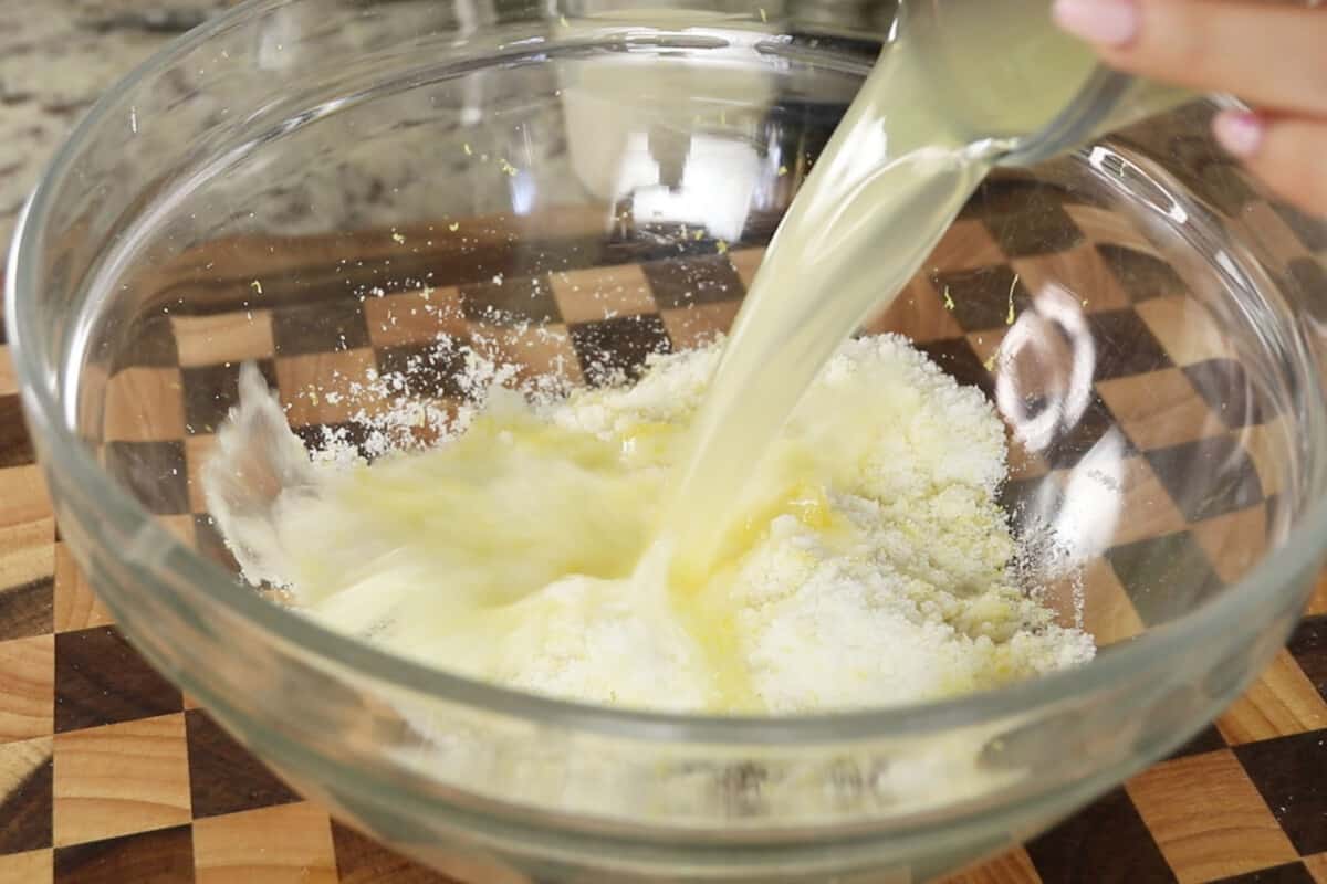 adding fresh lemon juice to large glass bowl for lemon loaf batter