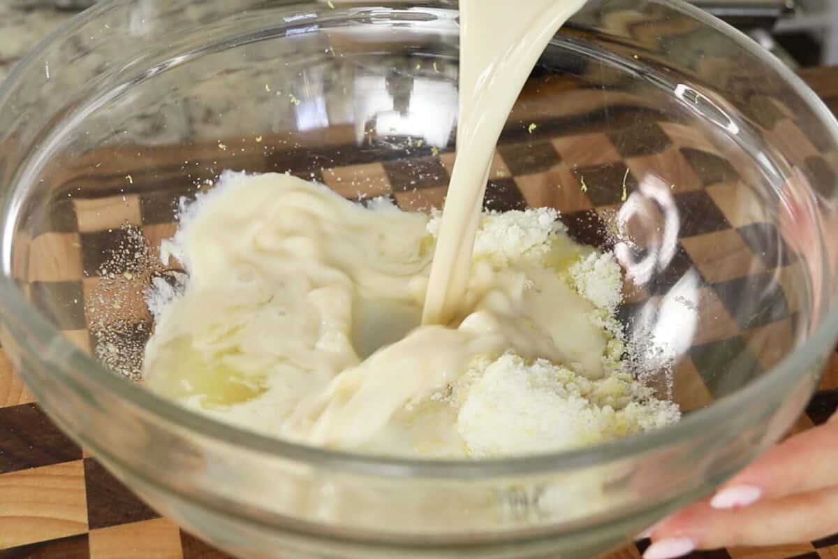 adding non-dairy milk to large glass bowl for lemon loaf batter