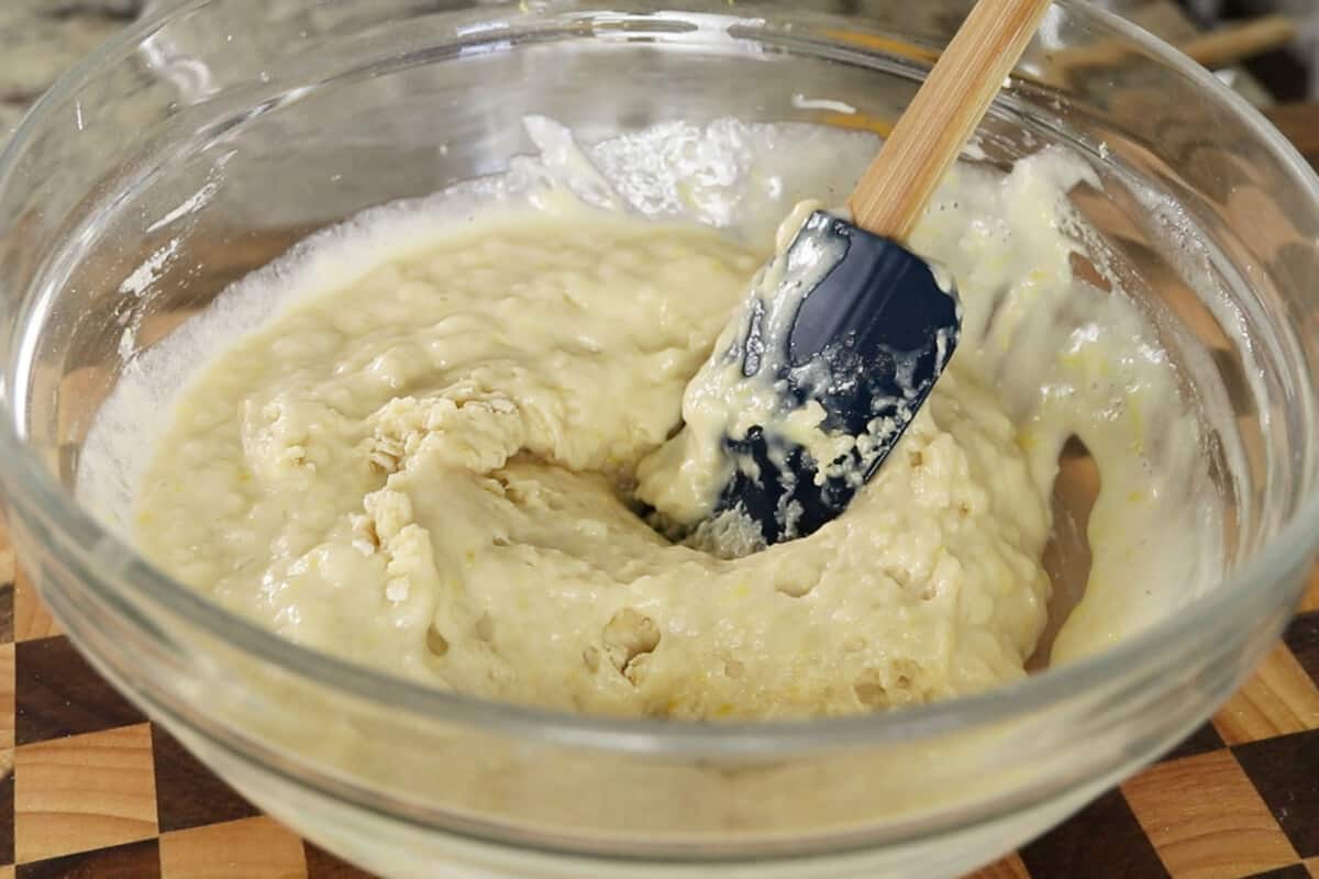 vegan lemon loaf batter in glass bowl with blue wooden spatula