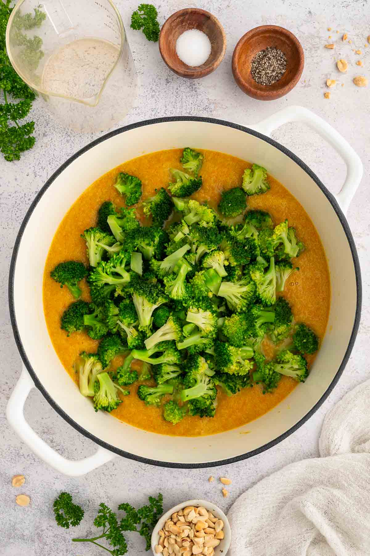 Broccoli and peanut butter soup being prepped with broccoli florets on top.