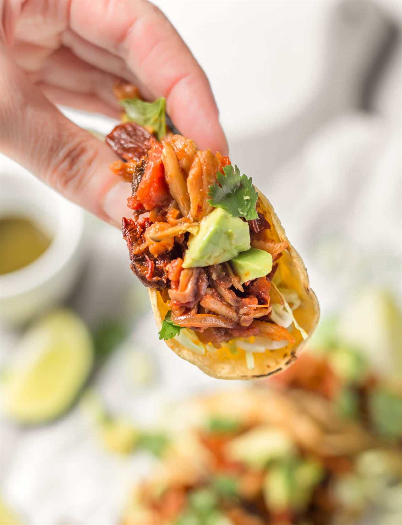 Hand Holding a Vegan Mushroom Taco Dressed With Avocado and Cilantro.