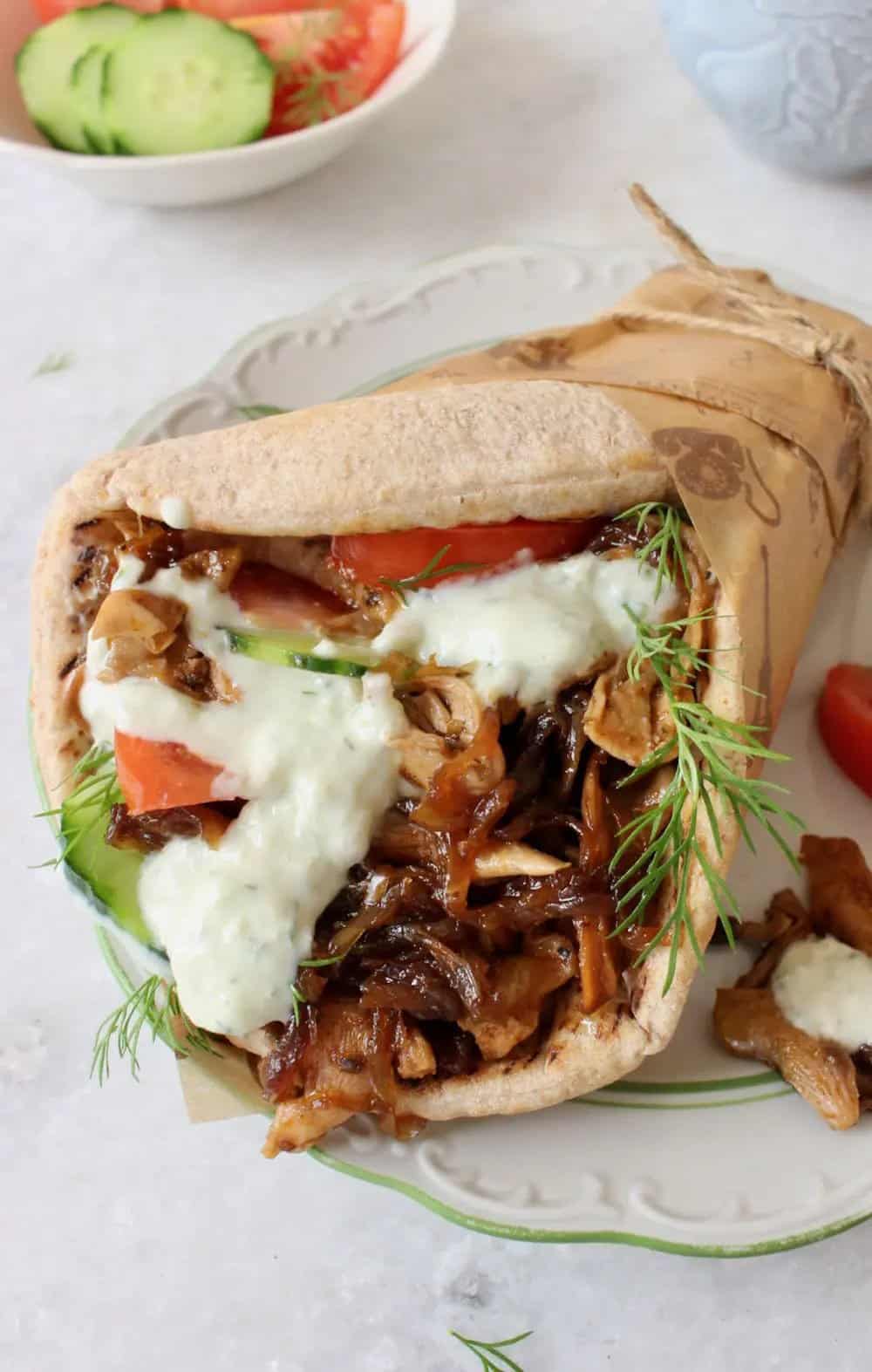 vegan oyster mushroom gyro in pita bread with sliced cucumbers, tomatoes, dill, and vegan tzatziki sauce