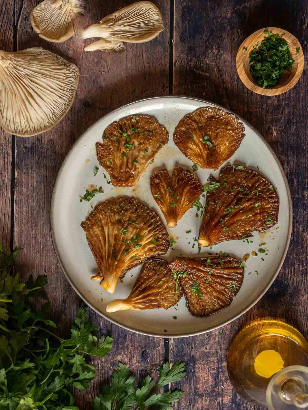 Air fried oyster mushrooms on a plate, sprinkled with fresh herbs.