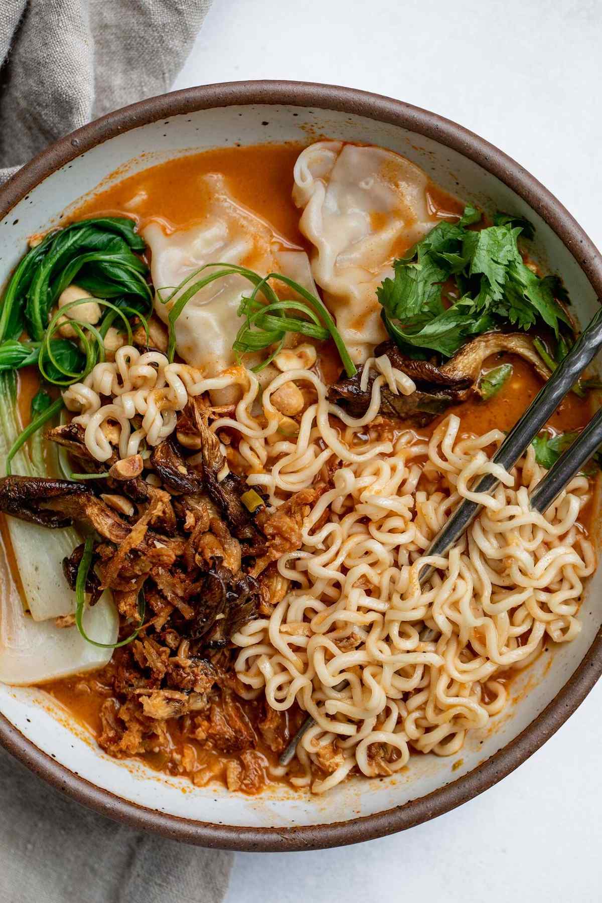 A bowl of peanut noodle soup with oyster mushrooms, boy choy, and cilantro.