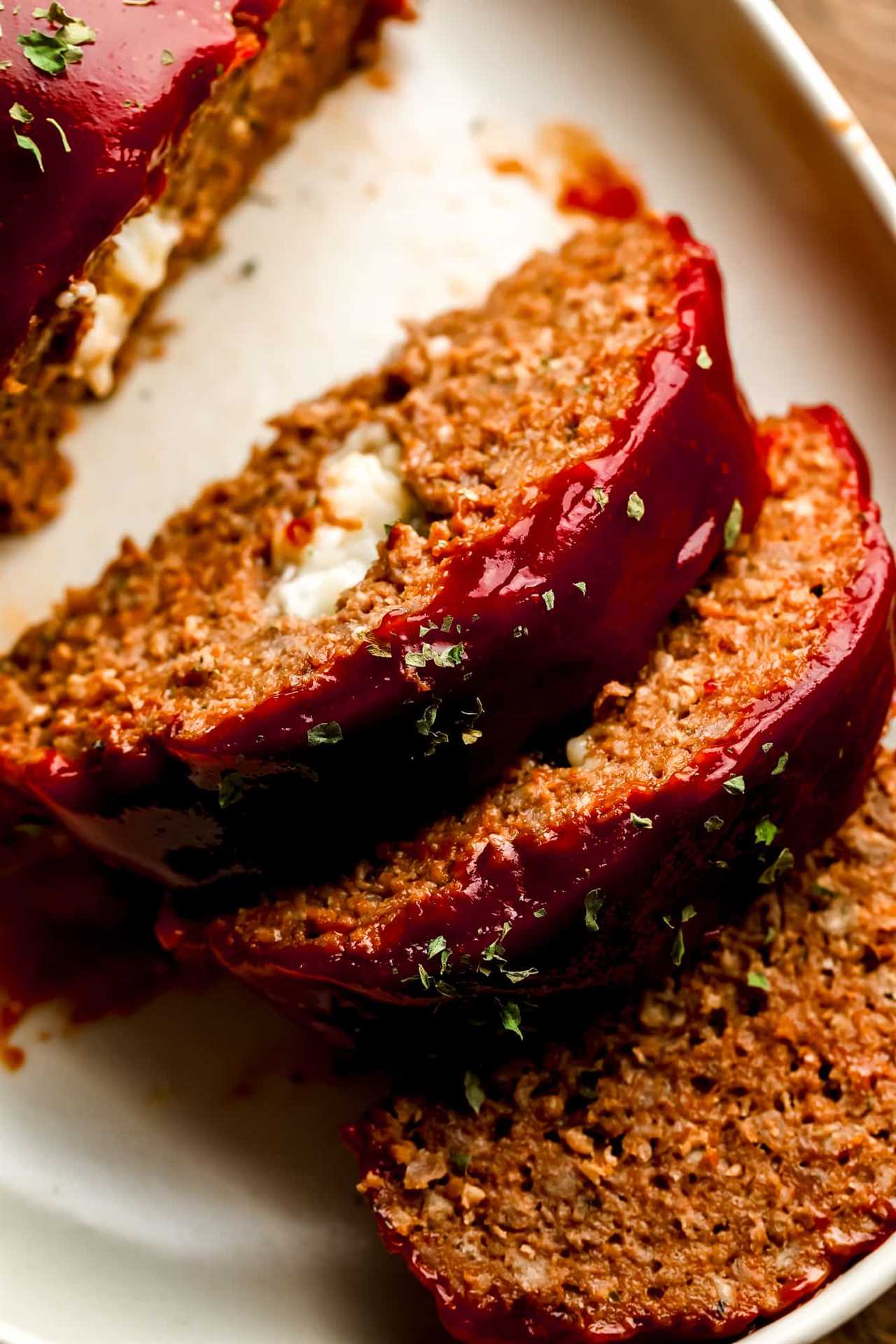 close up on slices of vegan Impossible meatloaf stuffed with vegan cheese and topped with a sticky red glaze.