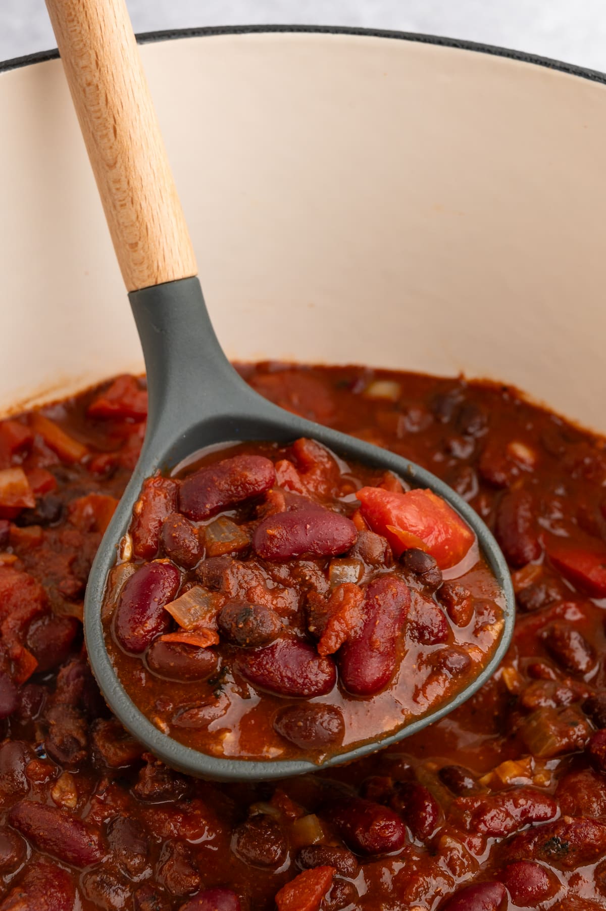 A ladle scooping up some vegan chili from the pot.