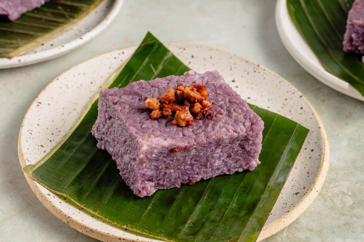 horizontal photo of a slice of filipino biko rice cake on a banana leaf on white plate