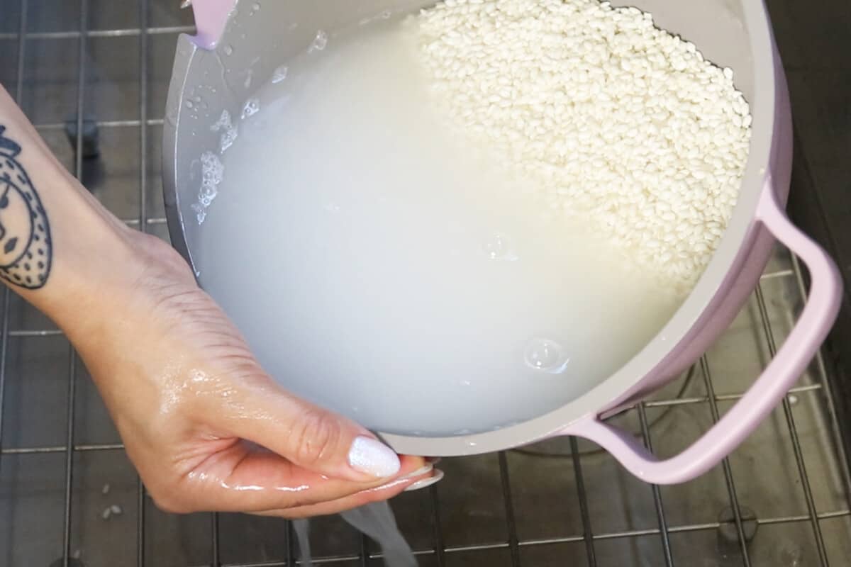 rinsing sweet rice in light purple pot in sink