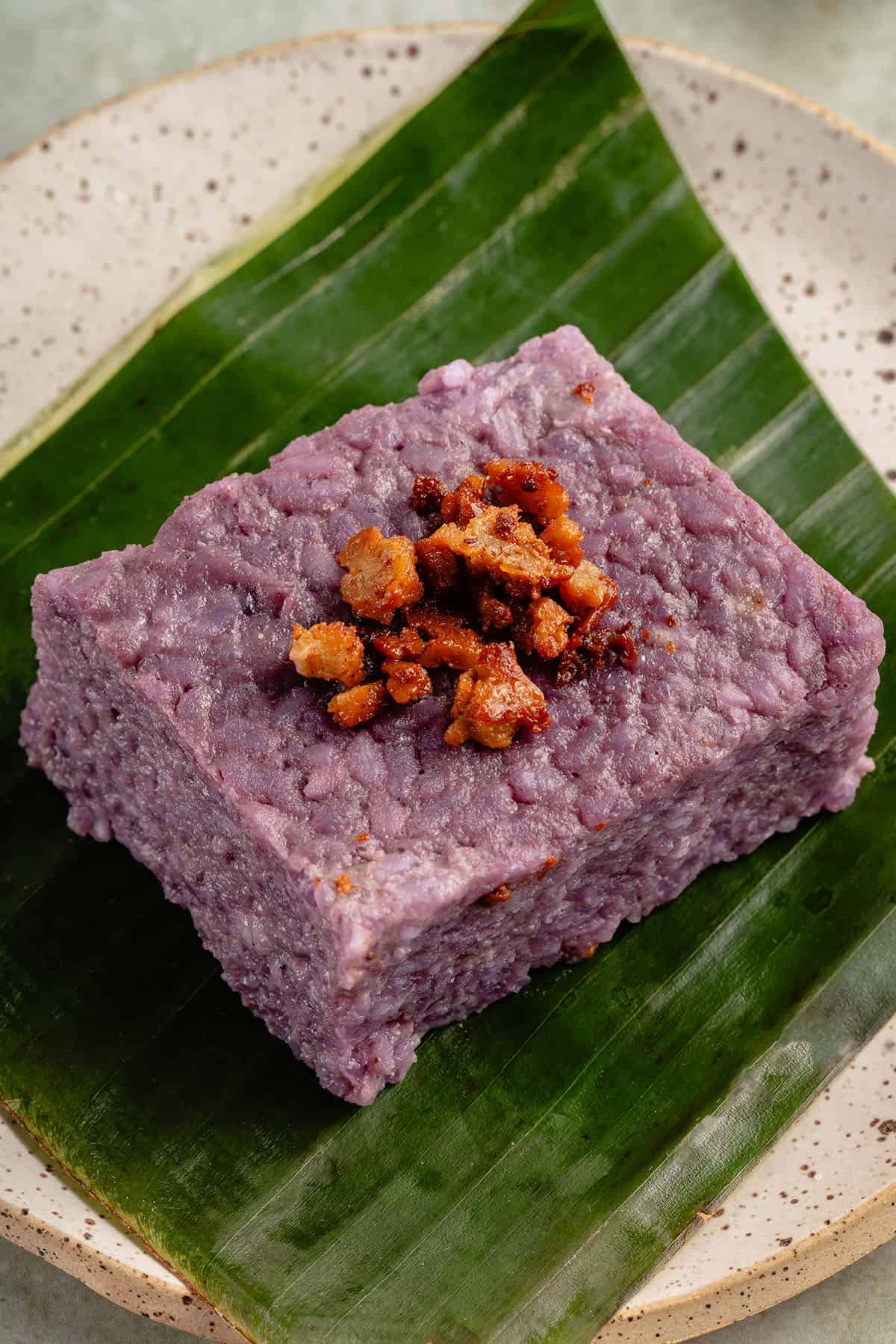 a slice of filipino biko rice cake on a banana leaf on white plate