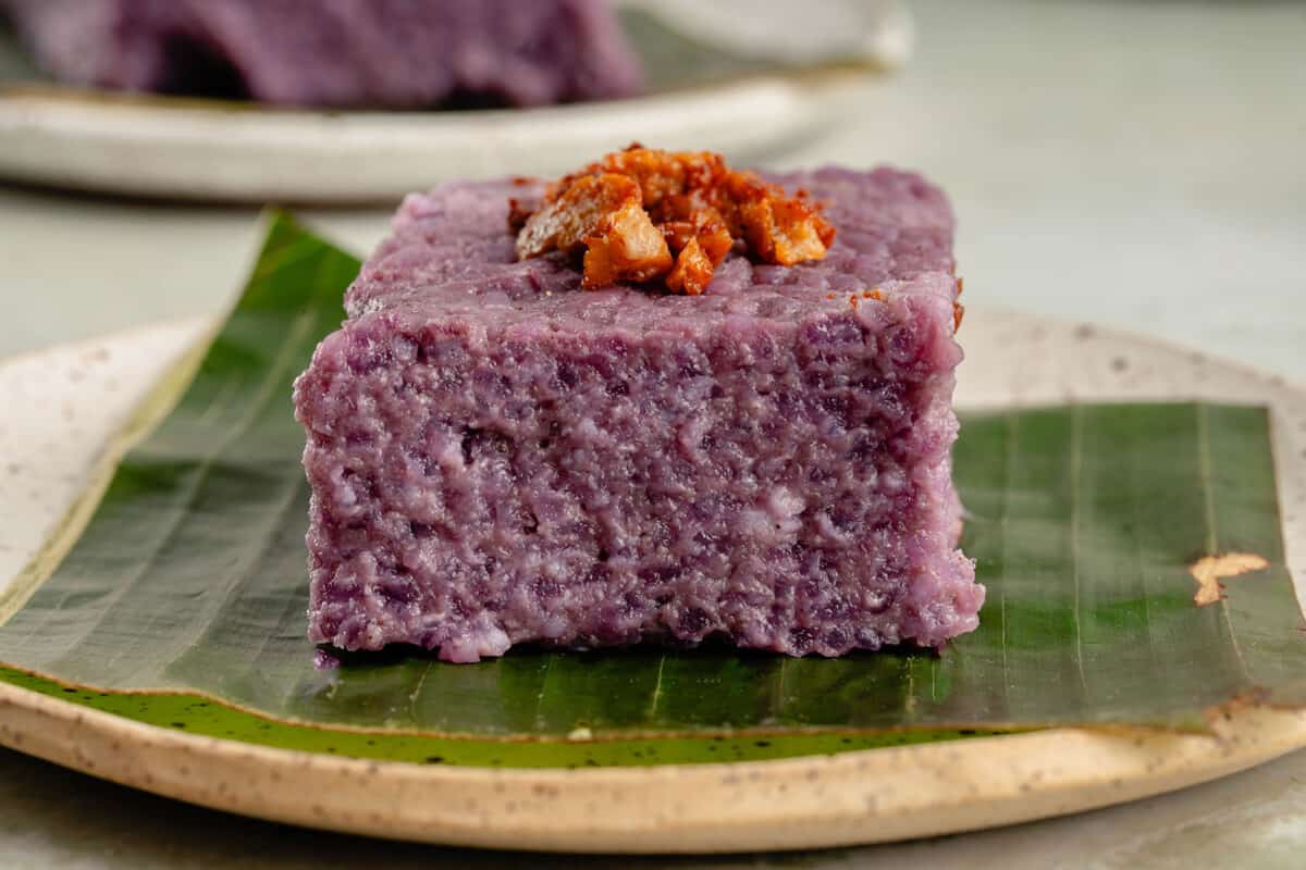 horizontal photo of a slice of filipino biko rice cake on a banana leaf on white plate