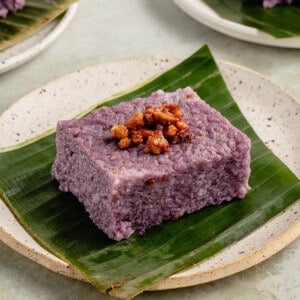 a slice of filipino biko rice cake on a banana leaf on white plate