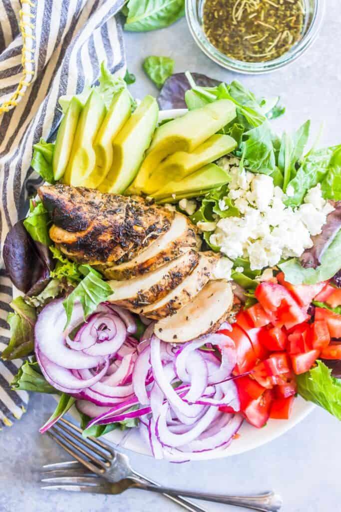 Keto Balsamic Chicken Salad in a bowl with a blue and white striped tea towel, jar of dressing, and forks to the side