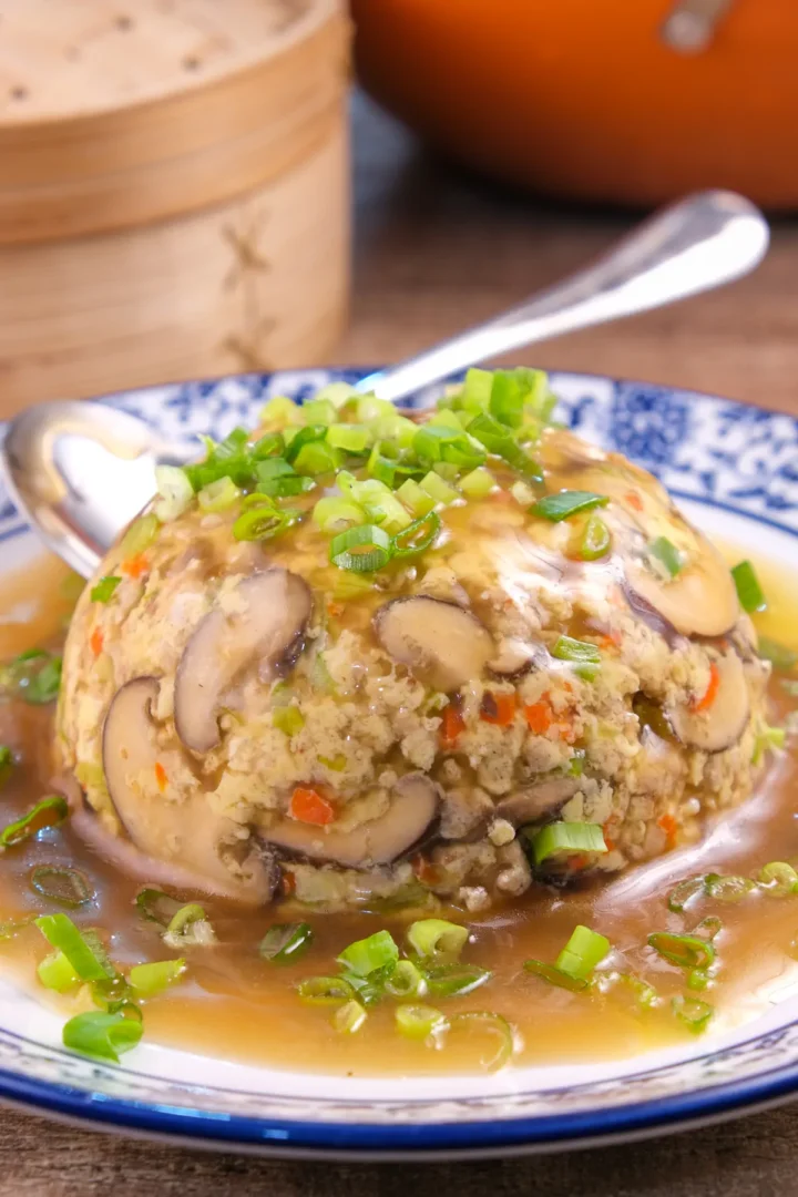 Keto egg foo young, shaped like a dome, with gravy served on a plate with a spoon.