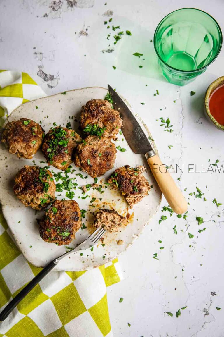 A plateful of rissoles with some parsley sprinkled over the top and some on a fork.
