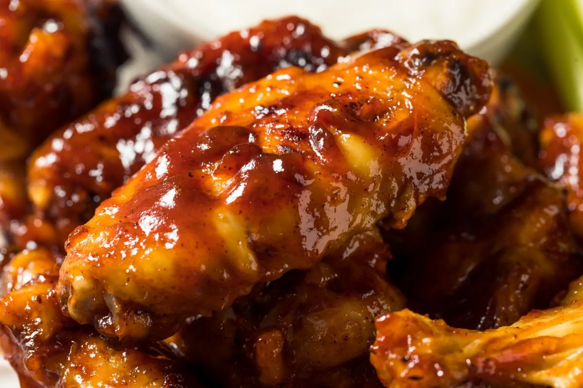 A close-up shot of BBQ sauce coated chicken wings.