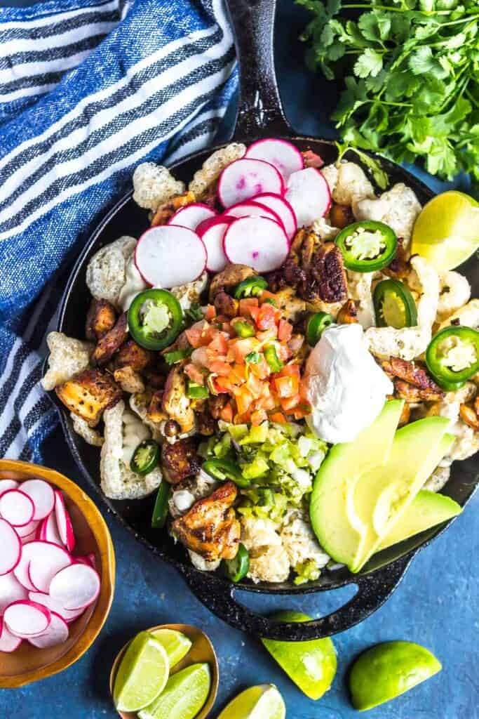 Keto Nachos in a cast iron skillet topped with chicken, cheese, pico de gallo, and more