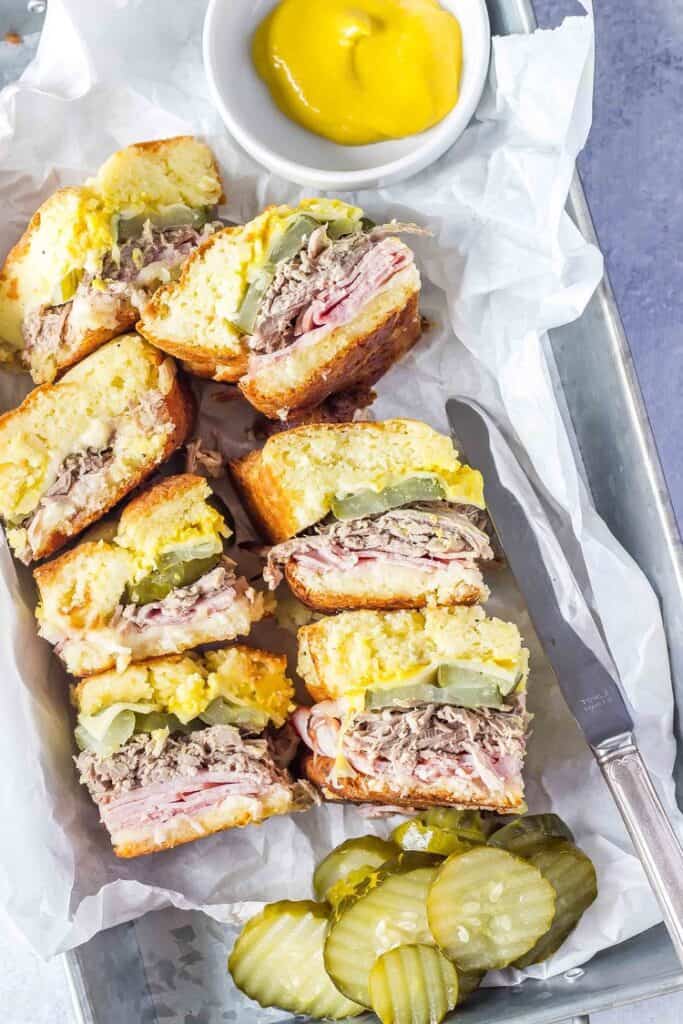 Keto Cuban Sliders in a tray with white parchment paper, pickles and mustard on the side